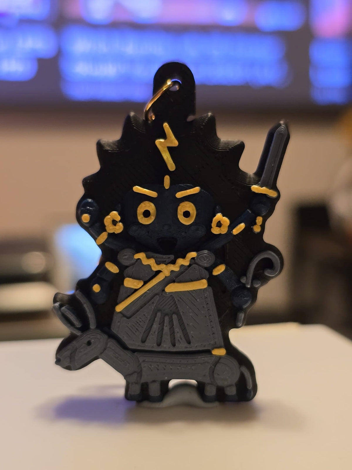 Kalaratri keychain: dark blue chibi devi with wild black hair, a gold lightning bolt, sword and iron hook, in a grey sari riding a donkey