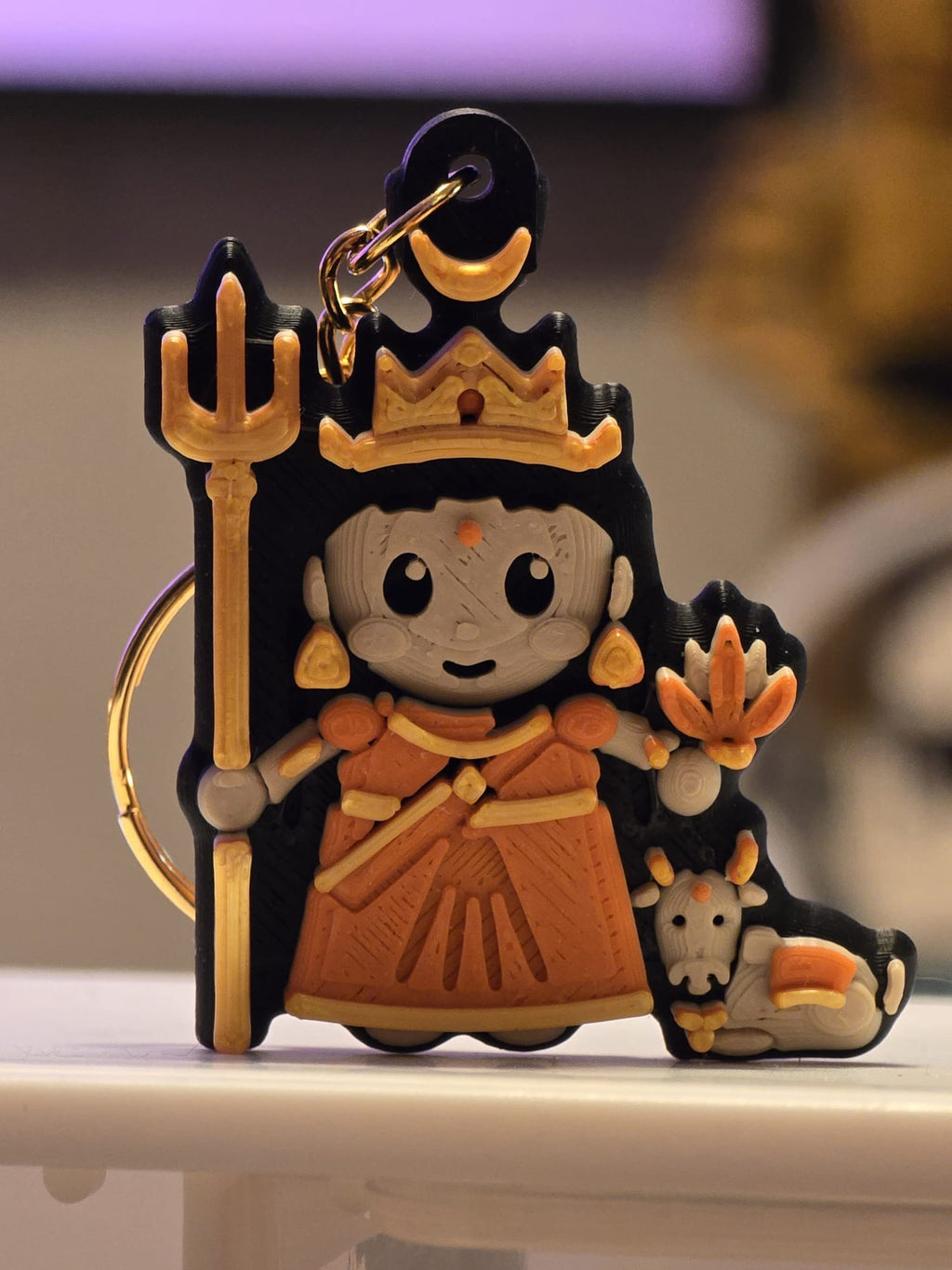 Shailaputri keychain: chibi devi in an orange sari holding a trishul and lotus, with Nandi the bull at her feet