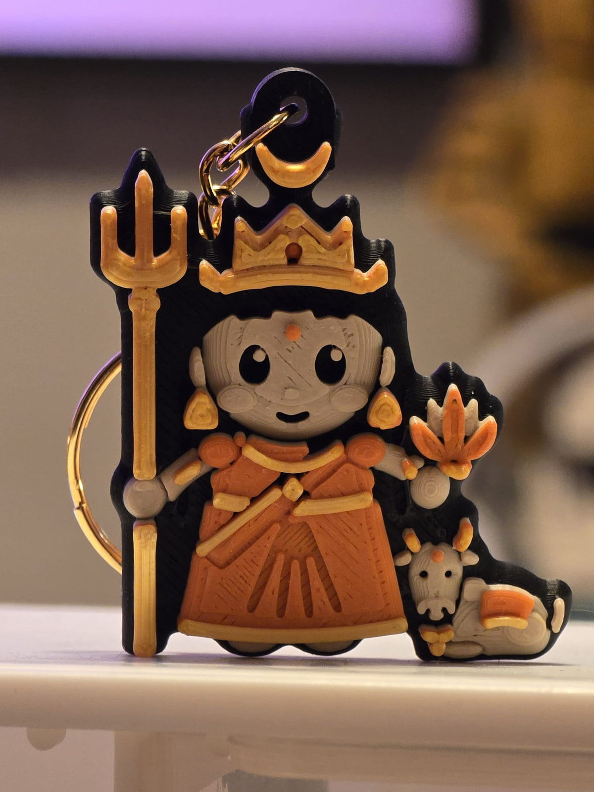 Shailaputri keychain: chibi devi in an orange sari holding a trishul and lotus, with Nandi the bull at her feet